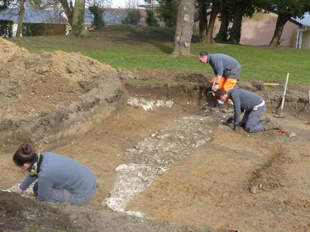 trois archéologues mettent au jour les fondations d'un bâtiment artisanal