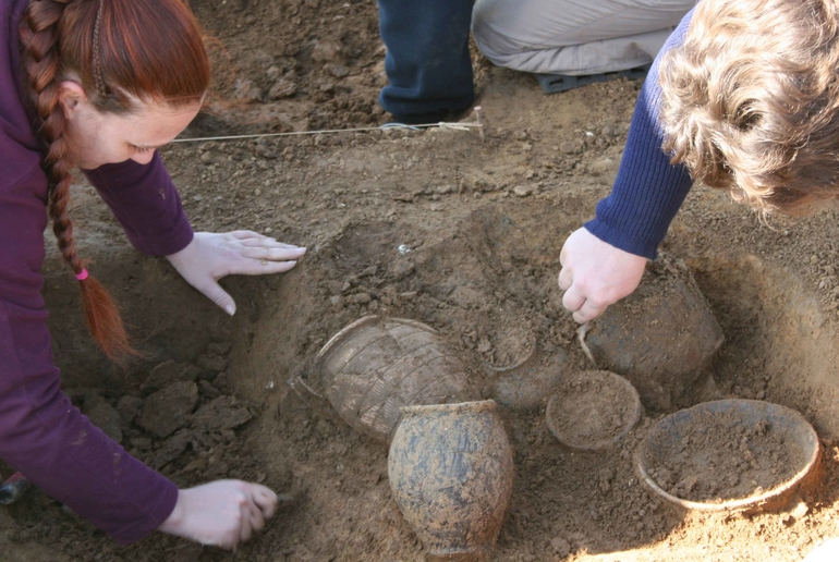 Dégagement de la vaisselle d'une tombe par les archéologues