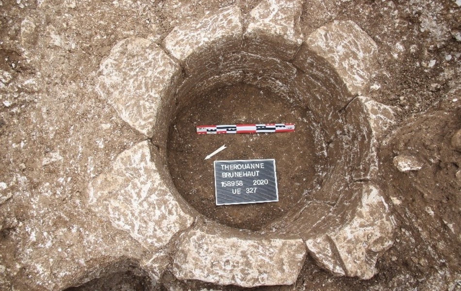 Vestiges d’un puits circulaire en pierre. La profondeur du puits est d’environ 1 mètre et le fond contient de la terre.