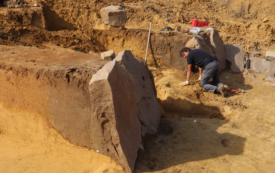 Plusieurs grandes pierres sont dressés contre une excavation.