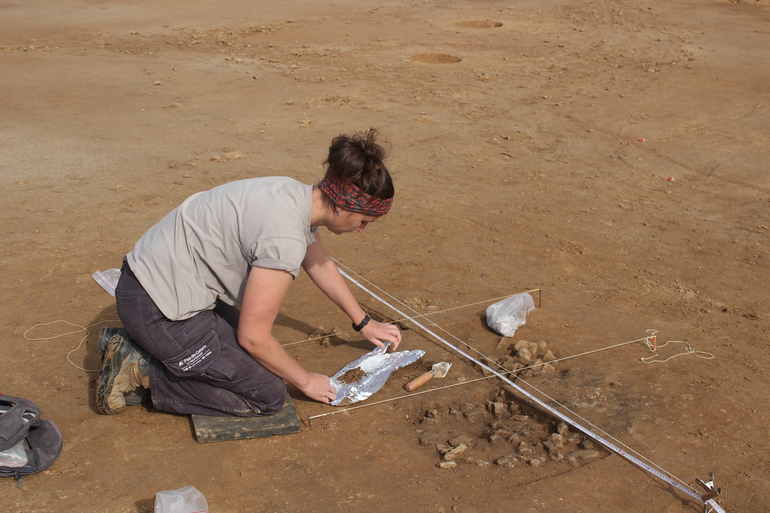 Une archéologue fouille un four à pièrres