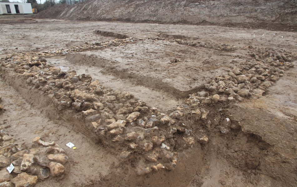 Photo des vestiges des fondations en rognons de silex du bâtiment le plus grand datant de la fin du Moyen Âge. 