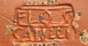 Photographie d'une inscription en relief FLOS C ATTIVS sur une poterie rouge